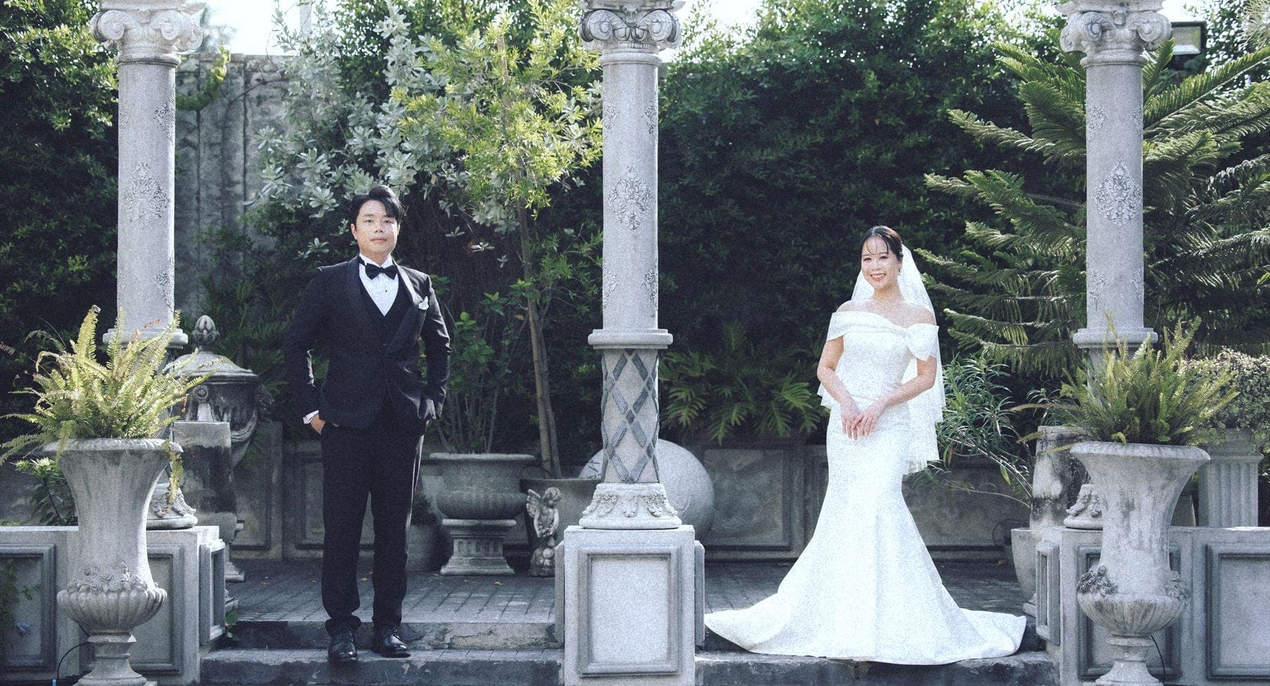 Witita and Sorratat standing between stone columns in a garden colonnade