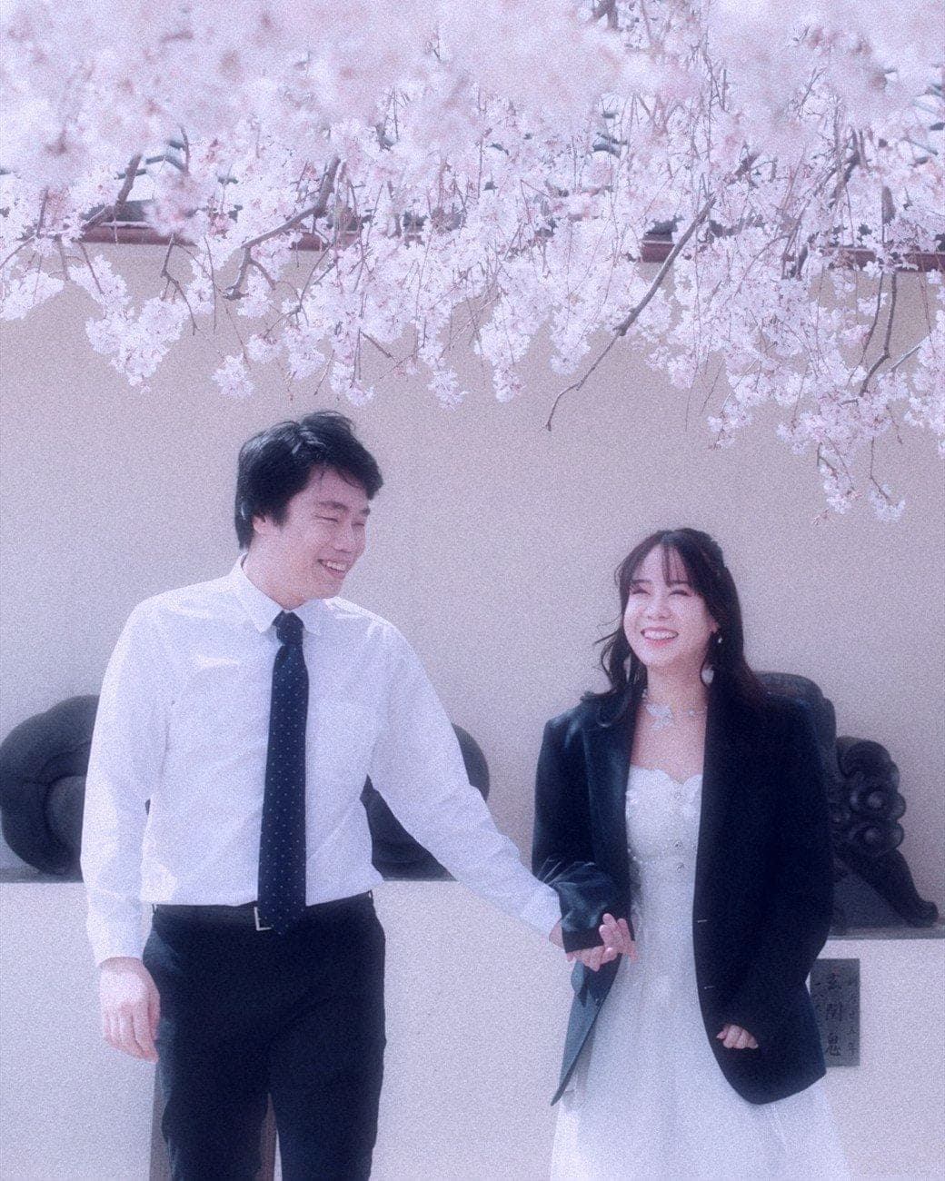 Witita and Sorratat hand in hand beneath cherry blossom in Japan