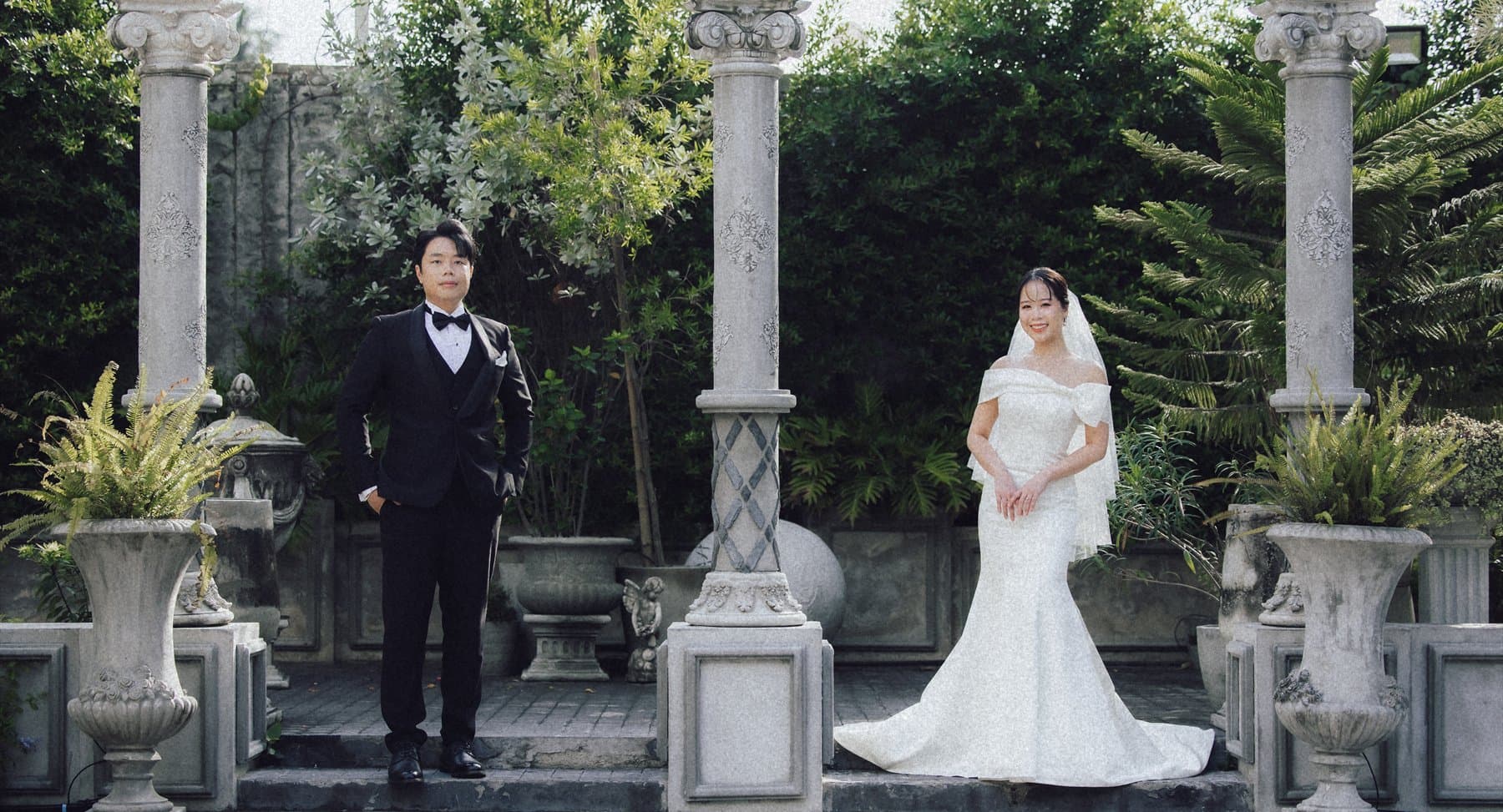 Witita and Sorratat standing between stone columns in a garden colonnade