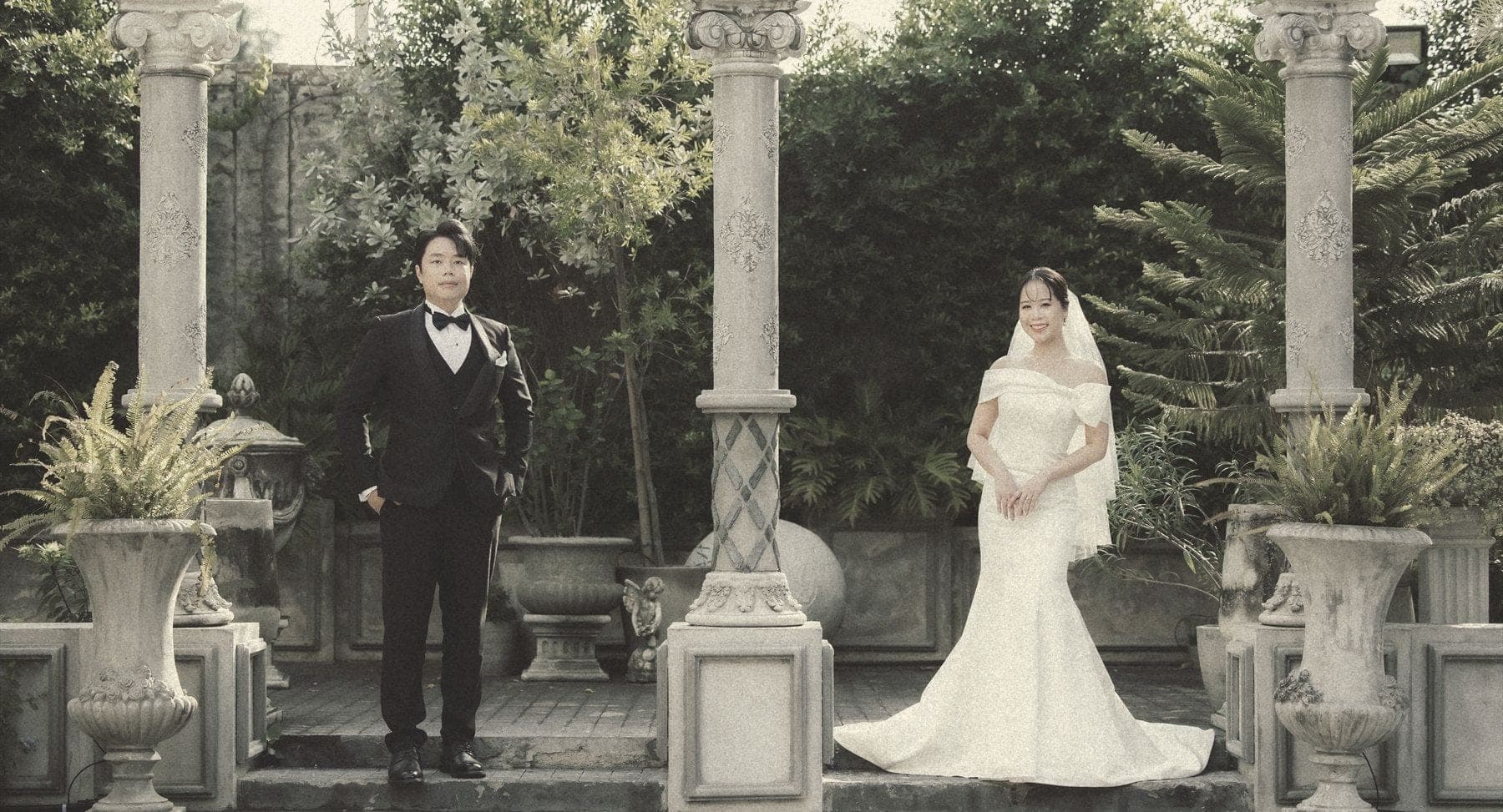 Witita and Sorratat standing between stone columns in a garden colonnade
