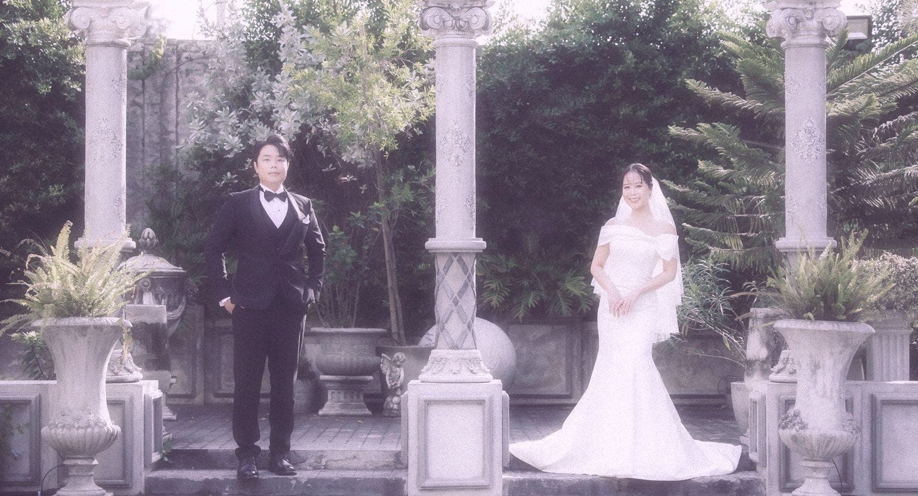 Witita and Sorratat standing between stone columns in a garden colonnade