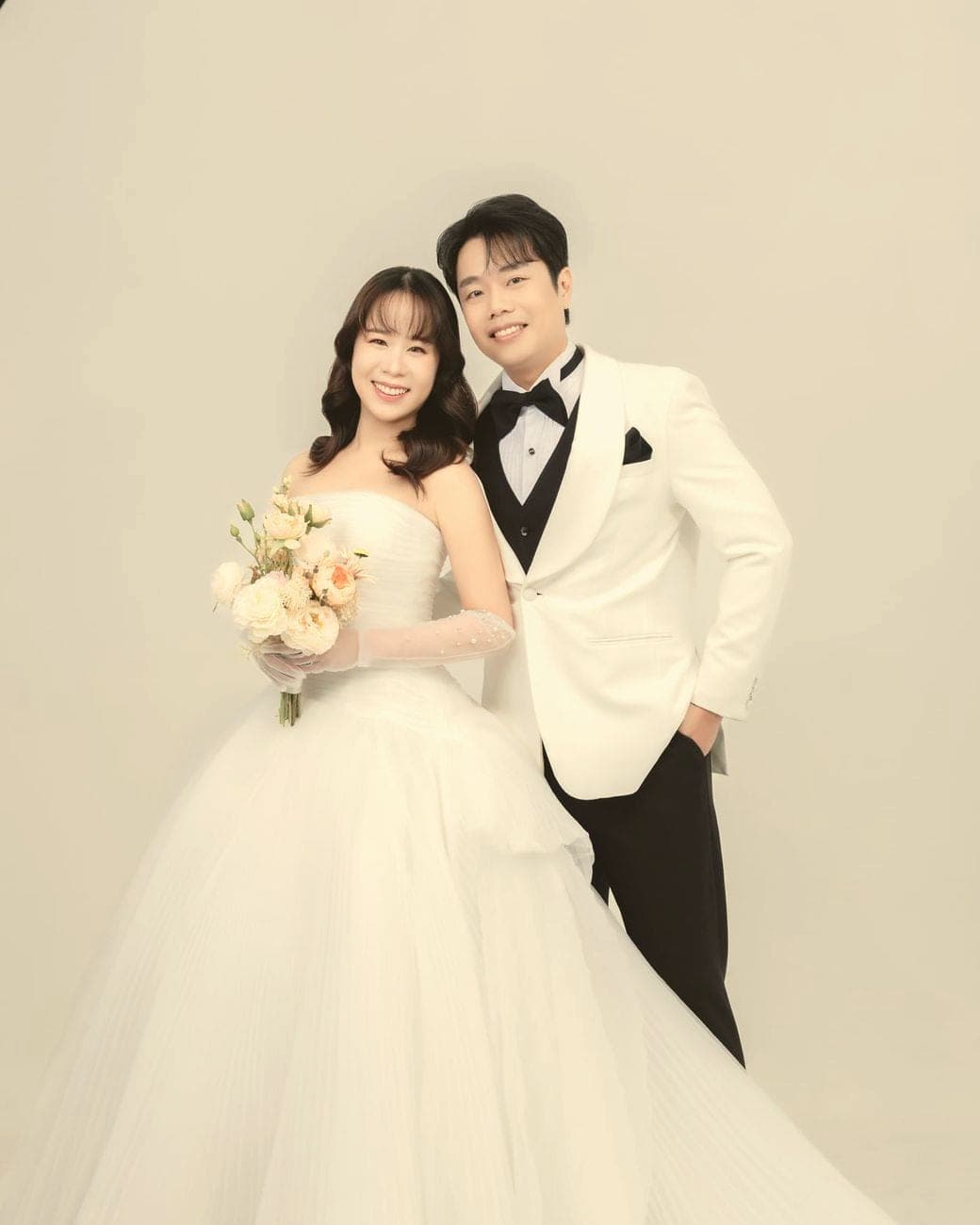 Sorratat in a white tuxedo standing behind Witita and her bouquet