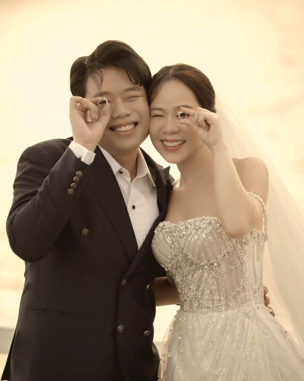 Witita and Sorratat laughing, making circles with their fingers like glasses