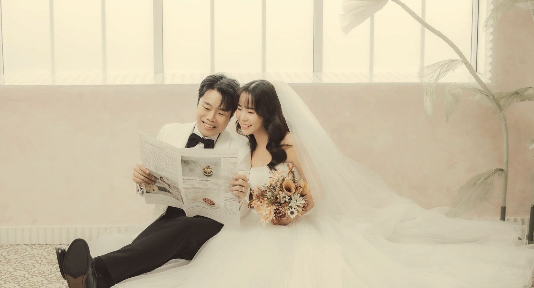 Witita and Sorratat sitting on the studio floor, reading a newspaper together